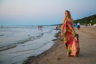 Beautiful girl in a dress walking down the beach